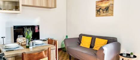 A compact living space with a dining area, a sofa, and a painting on the wall.