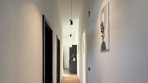 A modern hallway with a wooden floor, white walls, and black-framed doors. - Cosy apartment for 4 guests with WIFI, TV and balcony (Zell Am See)