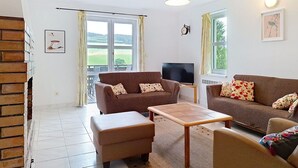 En stue med fjernsyn, to sofaer, et bord og en pejs.