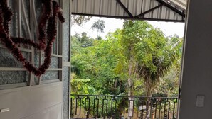 Eine offene Tür, die auf einen Balkon mit Blick auf üppiges Grün führt.