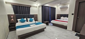 Habitación de hotel con dos camas, una mesita pequeña, una mesita de noche y un equipo de aire acondicionado.