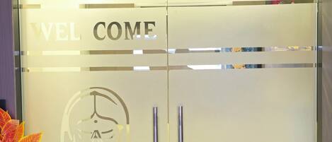 The entrance of Hotel Royal Villa with a frosted glass door and a welcome message.