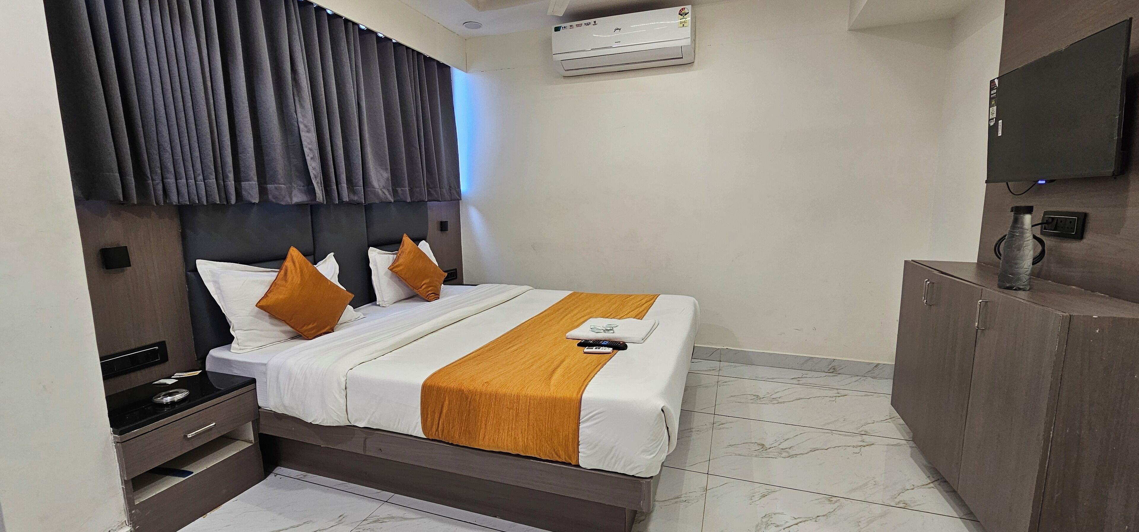 Una habitación de hotel con cama, mesita de noche, televisor y armario.
