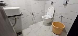 Un baño con inodoro, bidé y un balde.