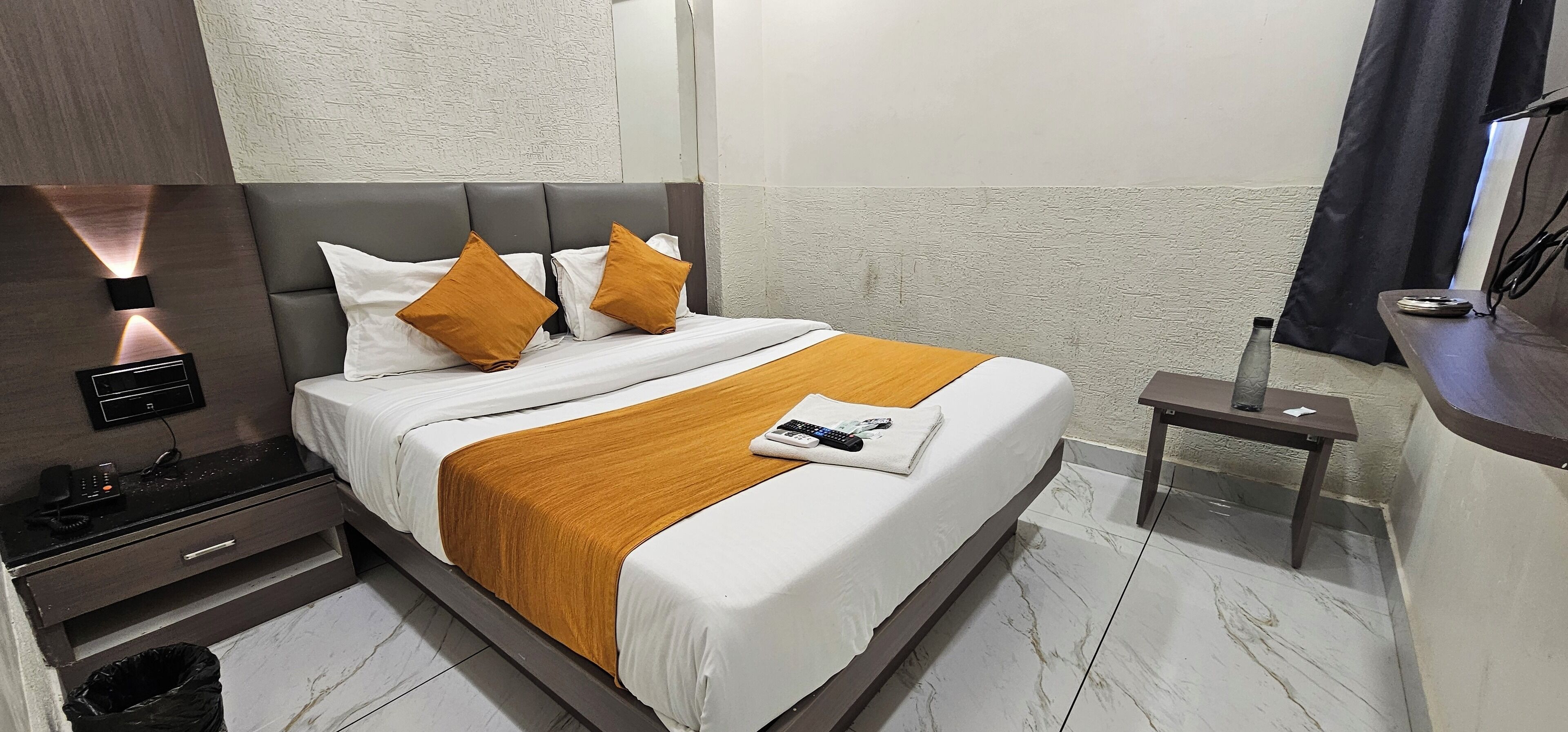 Une chambre d’hôtel équipée d’un lit, d’une table de chevet et d’un panneau de commande fixé au mur.