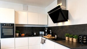 Eine moderne Küche mit weißen Schränken, einer schwarzen Arbeitsplatte und einem eingebauten Backofen.