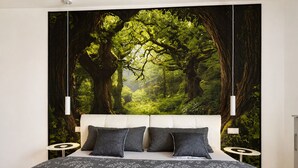 Ein Schlafzimmer mit einem großen Bett, zwei Nachttischen, einem Kopfteil und einem Wandbild mit Waldmotiv.
