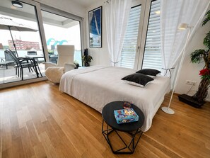 Une chambre moderne avec un grand lit, un coin repas avec des chaises, une petite table avec un jeu de société et une plante en pot.