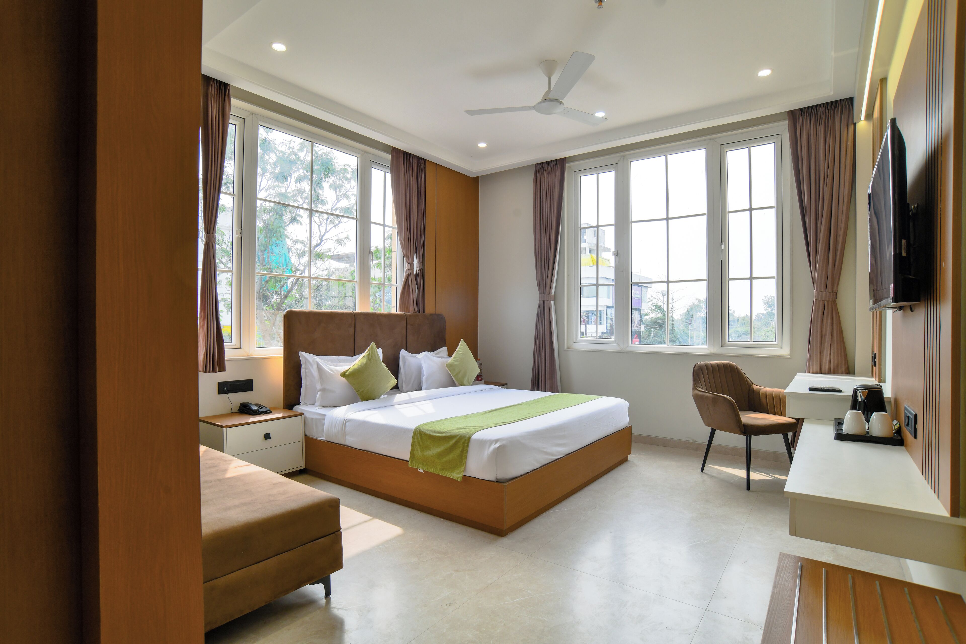 Una habitación de hotel moderna con una cama grande, un escritorio, una silla y un televisor.