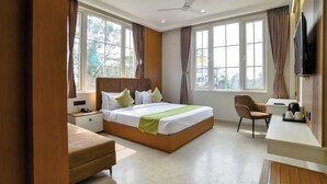 Una habitación de hotel moderna con una cama grande, un escritorio, una silla y un televisor.