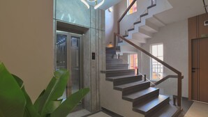 Un interior moderno con una escalera, un ascensor y una planta grande en maceta.