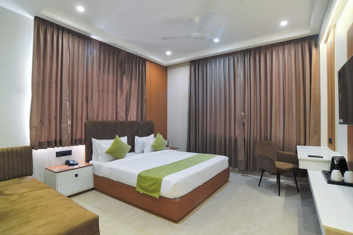 Ein modernes Hotelzimmer mit einem großen Bett, einem Schreibtisch, einem Stuhl und einem Deckenventilator.
