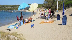 A beach with umbrellas, towels, and people relaxing. - THREE-ROOM APARTMENT HOUSE EMY C11 GROUND FLOOR WITH PATIO AND GARDEN (Golfo di Marinella)