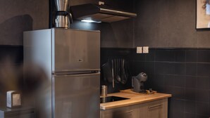Une cuisine moderne équipée d’un réfrigérateur en acier inoxydable, d’une machine à café et d’un plan de travail en bois.