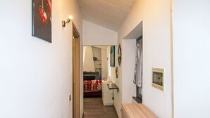Ein schmaler Korridor mit Holzboden, der in ein Schlafzimmer mit Bett und Nachttisch führt.
