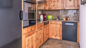 A compact kitchen with wooden cabinets, a stainless steel refrigerator, a microwave, a toaster, and a dishwasher. - Beautiful apartment for 5 guests with TV, patio, pets allowed and panoramic view (Silvaplana)
