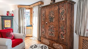 A room with a wooden wardrobe, a white sofa with red cushions, and a patterned ottoman. - Beautiful apartment for 5 guests with TV, patio, pets allowed and panoramic view (Silvaplana)