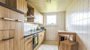 Eine kleine Küche mit Holzausstattung, einer Mikrowelle und einem Fenster.