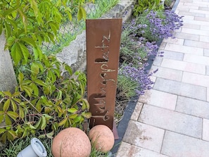 A metal sign with text, surrounded by greenery and a paved path. - Nice apartment for 4 people with WIFI and TV (Pirmasens)