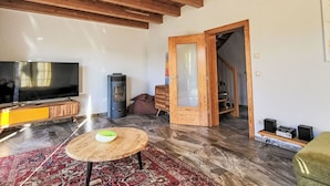 Un salon avec un plafond en bois, un téléviseur à écran plat, une cheminée, un canapé et une table basse.