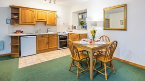 Une cuisine compacte dotée de meubles en bois, d’un lave-vaisselle encastré et d’un coin repas avec une table et des chaises.