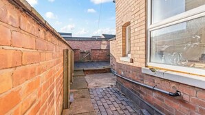 A narrow alleyway with brick walls, a window with a metal railing, and a visible door. - Spacious Warwick Stay | Contractors & Families (Warwick)
