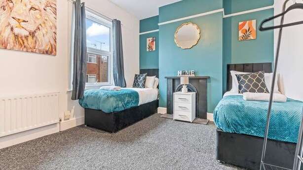 A bedroom with two beds, a window with curtains, a radiator, and artwork on the walls. - Spacious Warwick Stay | Contractors & Families (Warwick)