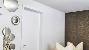 Une chambre à coucher avec un lit, des oreillers et un miroir mural agrémenté de plusieurs petits miroirs ronds.