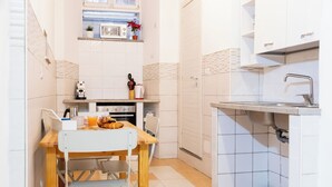 A compact kitchen with white cabinets, a microwave, a sink, and a dining area with a table and chairs. - Termini Volte Antiche & Comfort (Rome)