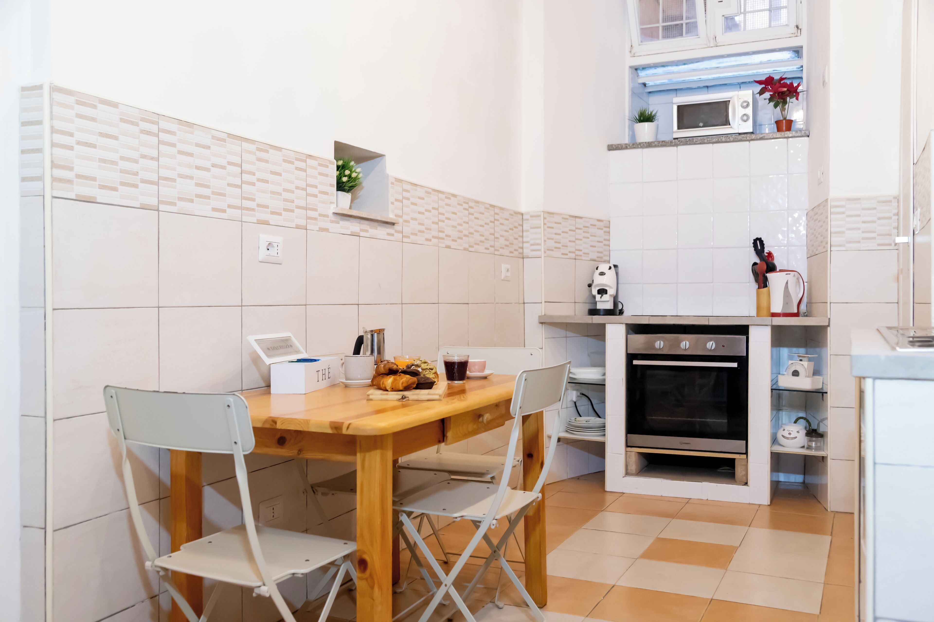 A compact kitchen with a wooden table, two foldable chairs, a microwave, and a built-in oven.