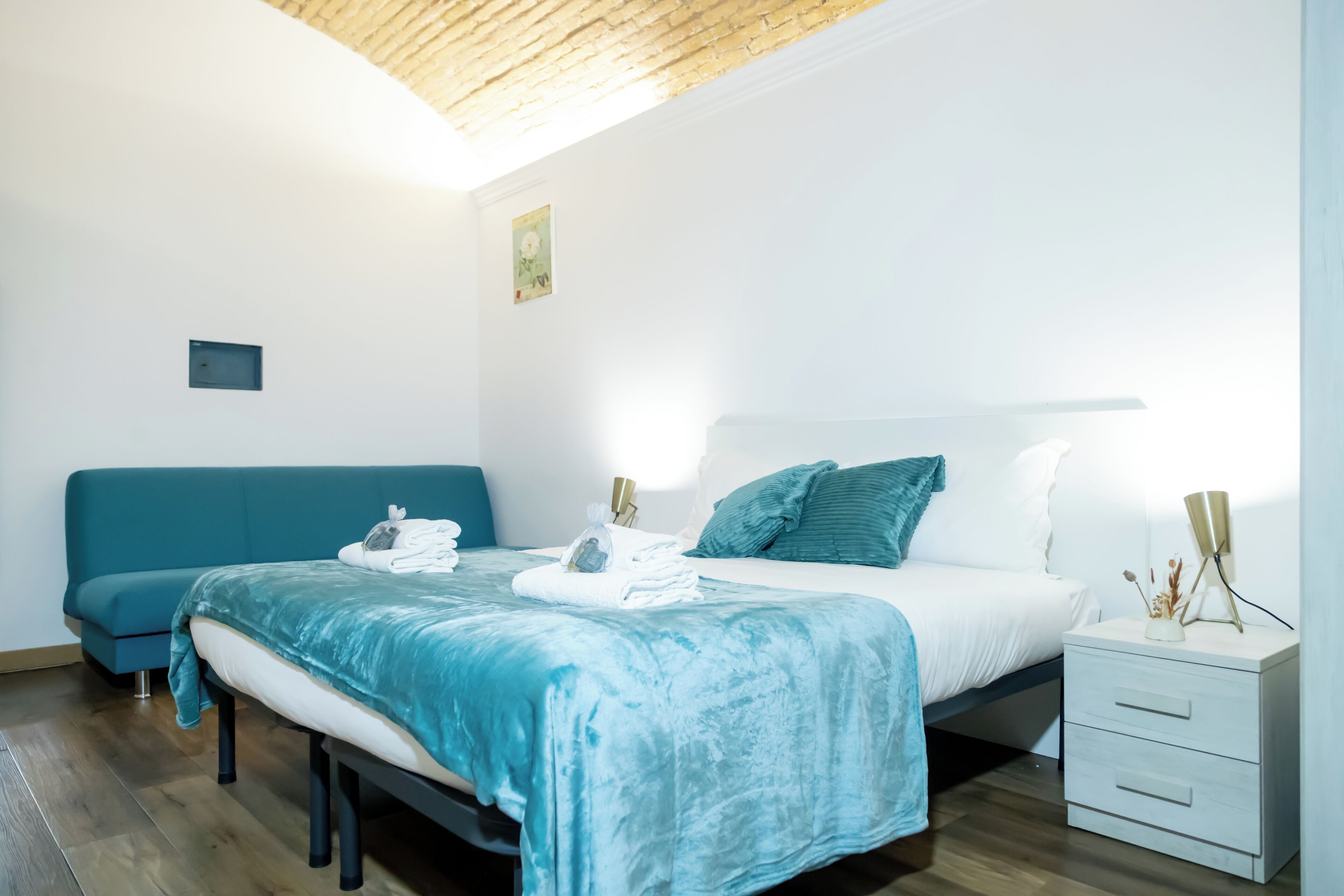 A modern bedroom with a bed, bedside table, and a small wall-mounted shelf.