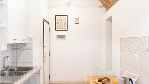 A compact kitchen with a tiled floor, a wooden dining table, and a white chair. - Termini Volte Antiche & Comfort (Rome)