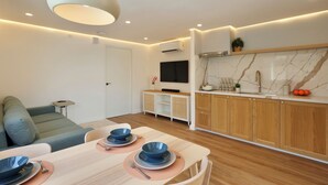 A modern kitchen with wooden cabinets, a marble backsplash, and a dining area with a table set for two.
