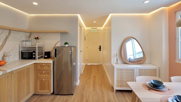 A modern kitchen with wooden cabinets, a built-in microwave, a stainless steel refrigerator, and a white countertop.
