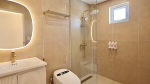 A modern bathroom with a glass-enclosed shower, a white sink with a round mirror, and a toilet with a digital display.