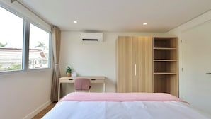 A bedroom with a bed, a desk, a chair, and a wardrobe.