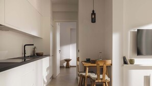 Une cuisine moderne avec des meubles blancs, un plan de travail noir et une table à manger en bois, accompagnée de chaises.