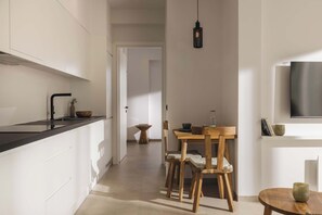 Une cuisine moderne avec des meubles blancs, un plan de travail noir et une table à manger en bois, accompagnée de chaises.