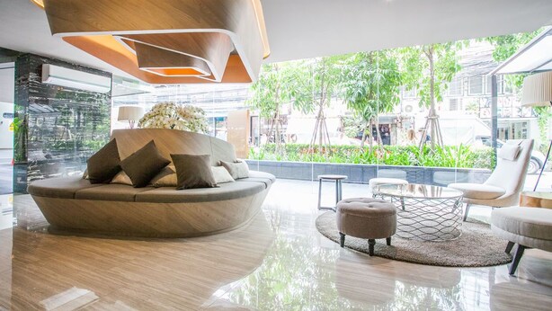 A modern interior with a curved sofa, ottoman, and a glass coffee table.