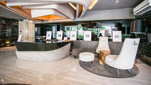 A modern reception area with a curved desk, white chairs, and framed pictures on the wall.