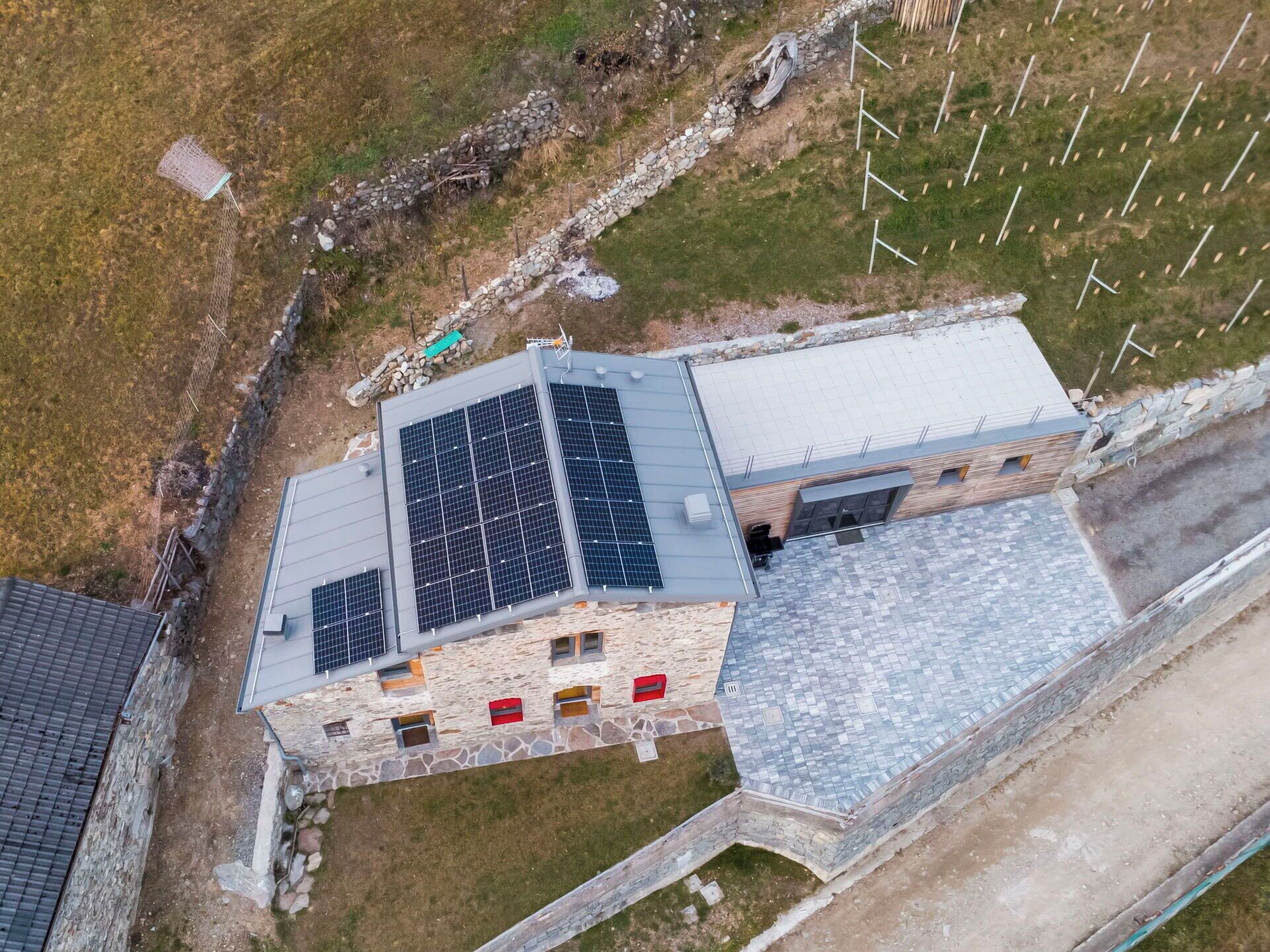 Un edificio in pietra con tetto spiovente, pannelli solari e una parete in pietra.