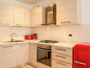 Eine moderne Küche mit hellen Holzschränken, Edelstahlgeräten und einem roten Kühlschrank.