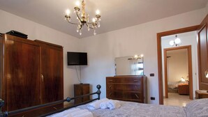 Ein Schlafzimmer mit einem großen Bett, einem Holzschrank, einem Fernseher, einem Spiegel und einer Chandelüster.