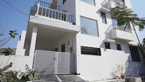A multi-story building with balconies, large windows, and a gated entrance. - The Nivaas At Jagir Villa (Udaipur)