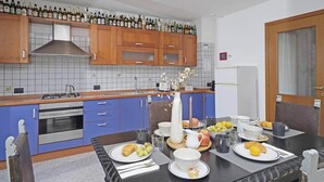 Eine moderne Küche mit Holzschränken, einem Gasherd und einem Essbereich mit gedecktem Tisch zum Frühstück.