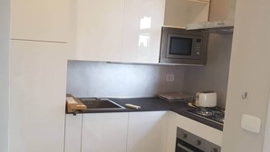 A compact kitchen with a microwave, toaster, and oven. - Modern Flat with lake view & private beach! (Toscolano-Maderno)