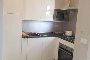 A compact kitchen with a microwave, toaster, and oven. - Modern Flat with lake view & private beach! (Toscolano-Maderno)