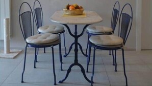 A dining area with a round table, four chairs, and a fruit basket. - Modern Flat with lake view & private beach! (Toscolano-Maderno)