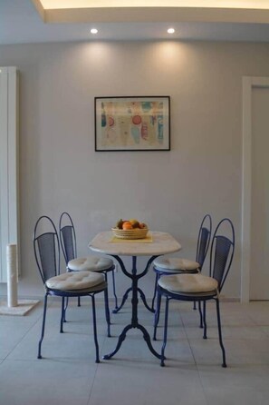 A dining area with a round table, four chairs, and a fruit basket. - Modern Flat with lake view & private beach! (Toscolano-Maderno)