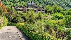Un hotel a più piani con un cortile centrale, circondato da vegetazione lussureggiante e una collina sullo sfondo.